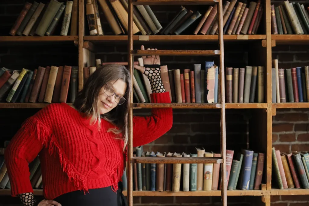 photo of Stephanie Threadgill, the founder and owner of SMH Social Management, in front of a bookcase and next to bookcase ladder.